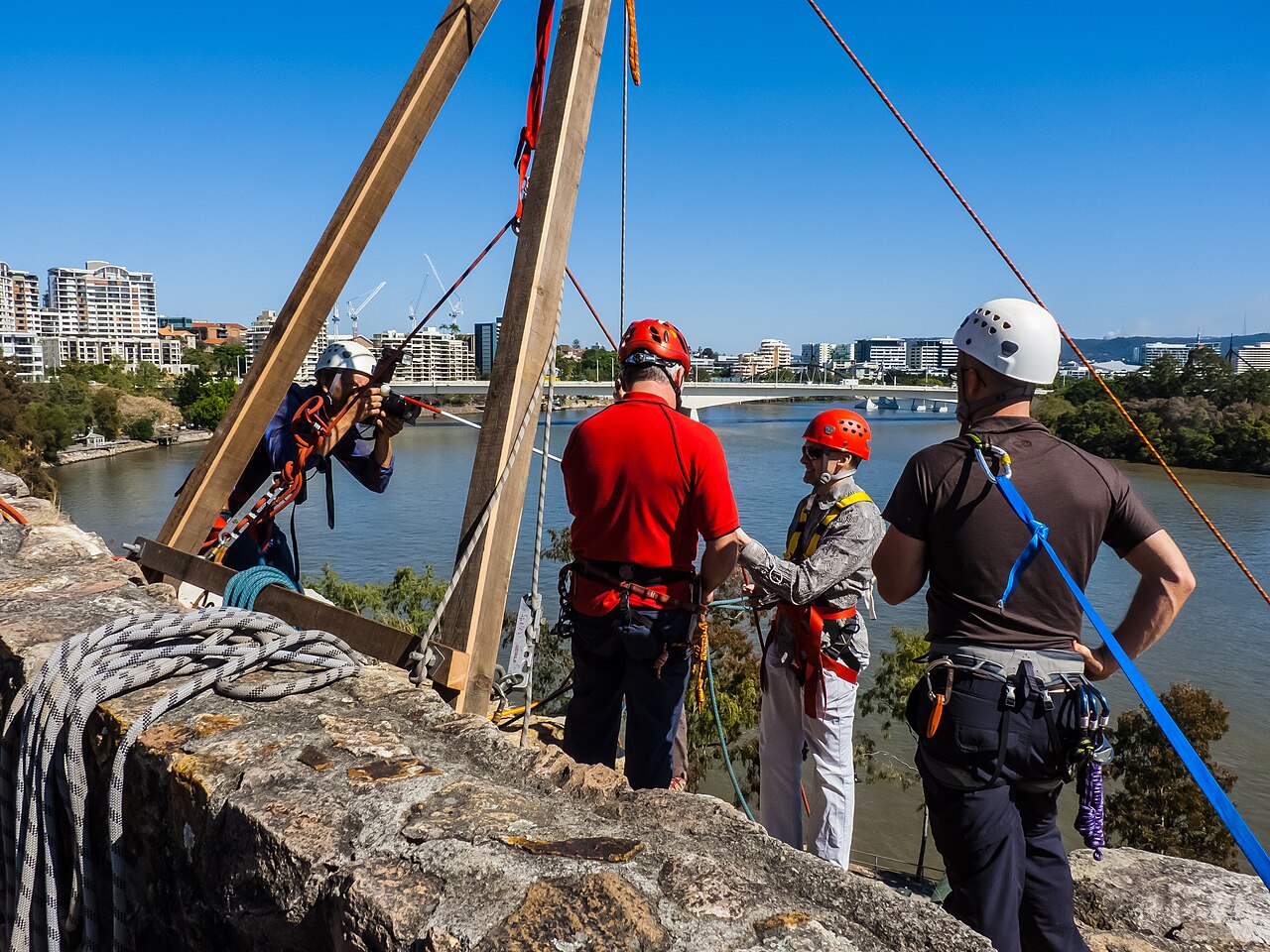 John Robert McPherson · CC BY-SA 4.0 · https://creativecommons.org/licenses/by-sa/4.0 · https://commons.wikimedia.org/wiki/File:NDIS_Promotion_abseiling_Kangaroo_Point_cliffs_River_Tce_Kangaroo_Point_Brisbane_P1160270.jpg A small group and instructors preparing at the top of an abseil