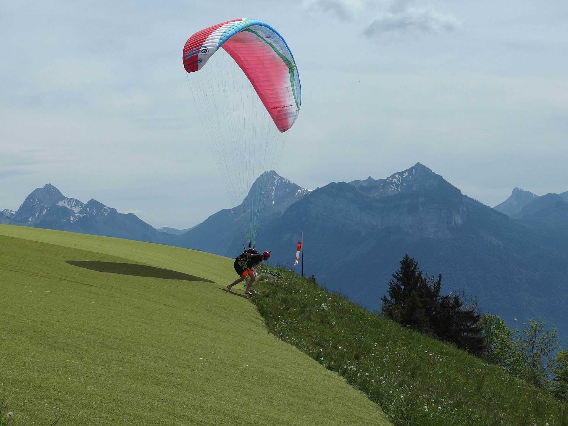 Guilhem Vellut from Annecy, France · CC BY 2.0 · https://creativecommons.org/licenses/by/2.0 · https://commons.wikimedia.org/wiki/File:Paragliders_@_Col_de_la_Forclaz_@_Hike_to_Pointe_de_la_Rochette_(15094623338).jpg A tandem paraglider launching at Col de la Forclaz above Lake Annecy