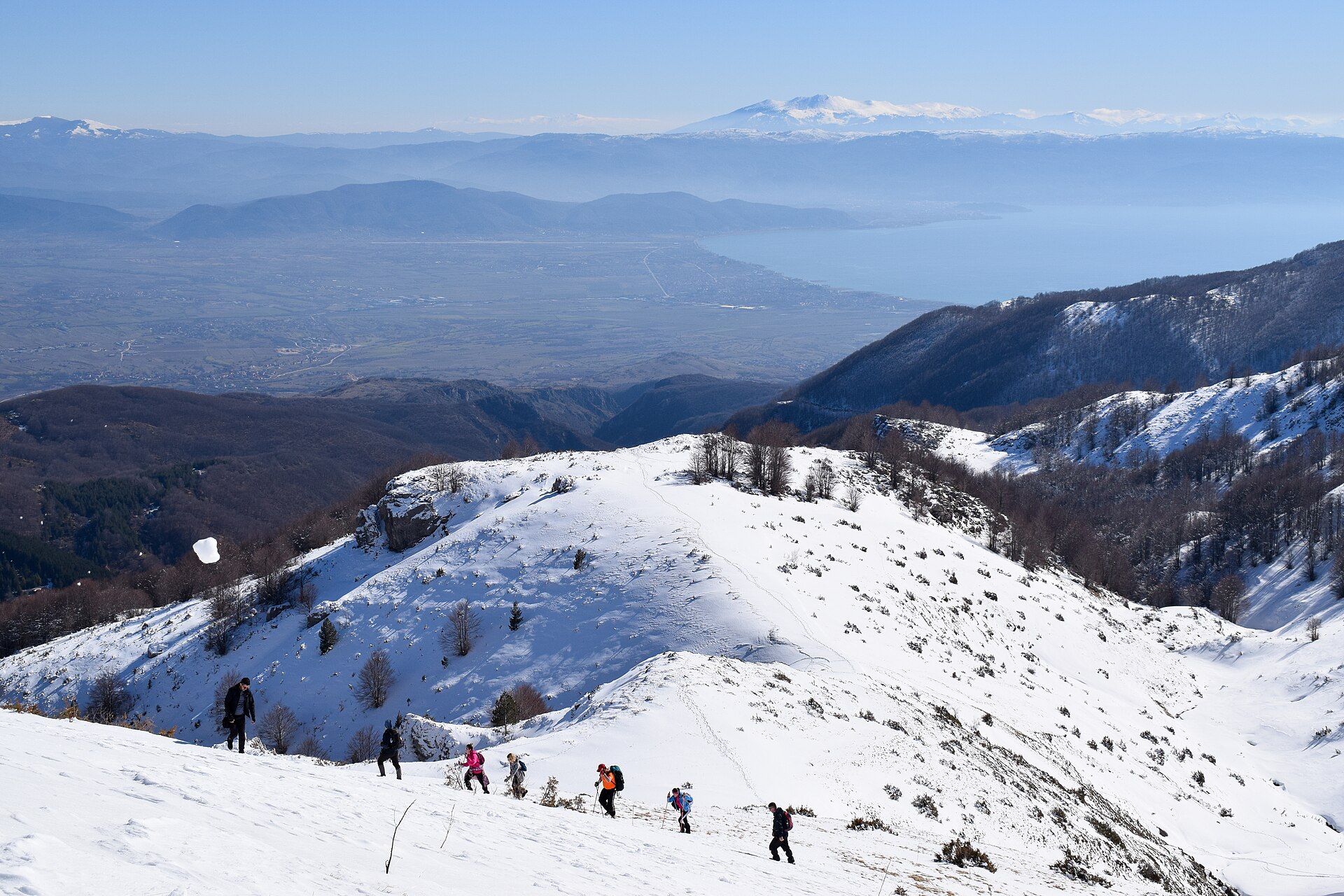 Liridon · CC BY-SA 4.0 · https://creativecommons.org/licenses/by-sa/4.0 · https://commons.wikimedia.org/wiki/File:Hikers_in_Jablanica_mountain_in_winter_2020,_in_background_Struga,_Lake_of_Ohrid,_and_Pelister_peak.jpg A group ascending snow-covered mountain terrain in Jablanica