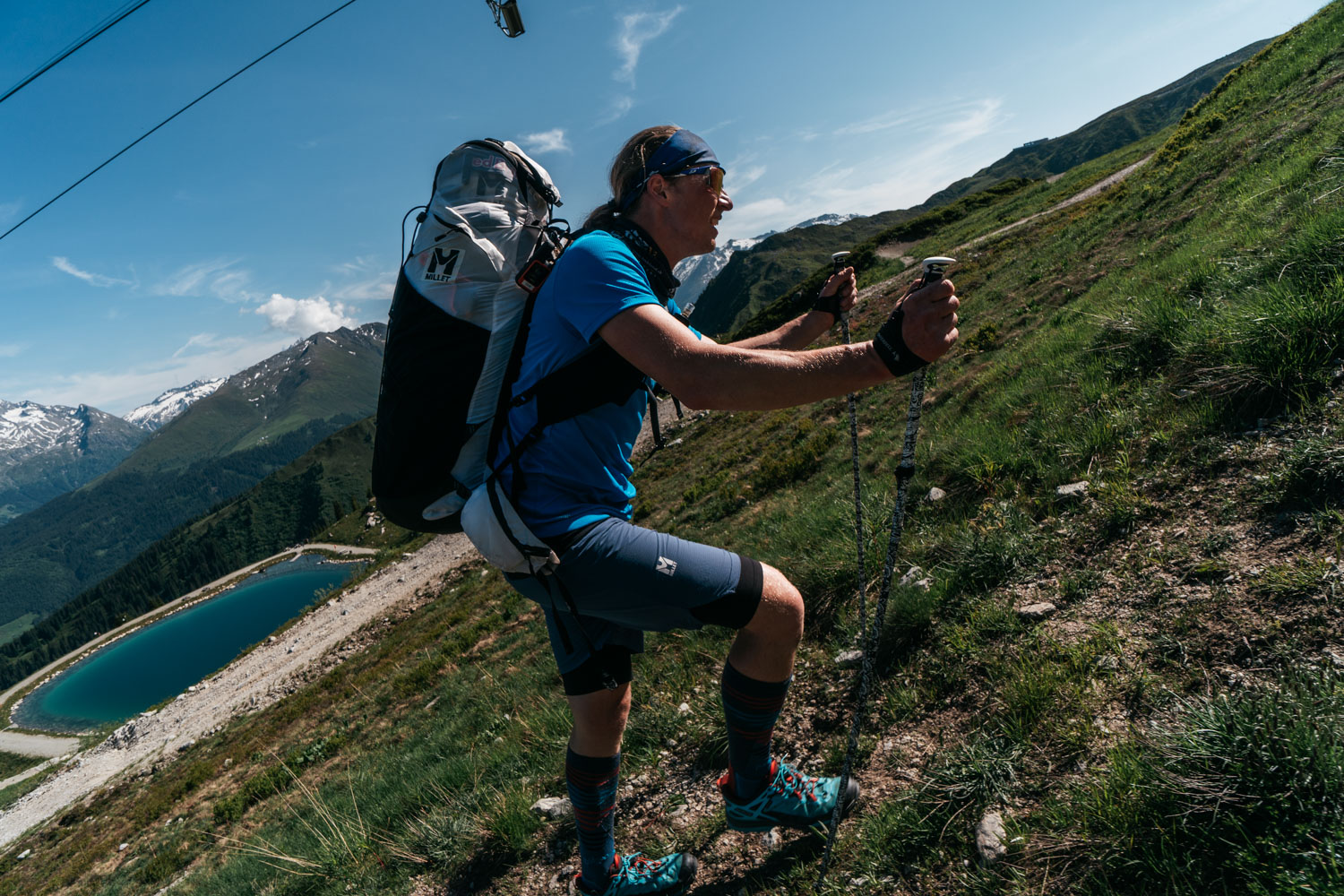 Juraj Koreň · CC BY-SA 4.0 · https://creativecommons.org/licenses/by-sa/4.0 · https://commons.wikimedia.org/wiki/File:Red_Bull_X-Alps_2025_-_Hike%26Fly.jpg A hike-and-fly pilot ascending with paragliding equipment during the 2025 X-Alps event