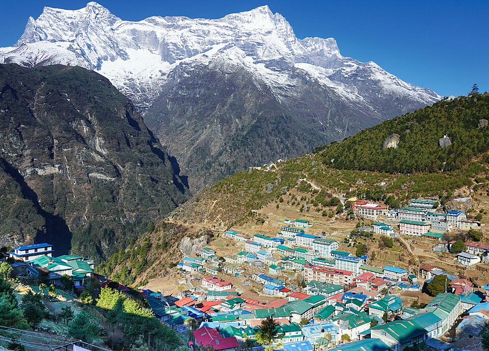 Nirojsedhai · CC BY-SA 4.0 · https://creativecommons.org/licenses/by-sa/4.0 · https://commons.wikimedia.org/wiki/File:Namche_Bazaar_facing_Kongde_Ri_towards_west.jpg · Displayed cropped to fit Namche Bazaar below Kongde Ri
