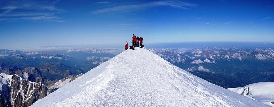 Climbers standing on the snowy summit of Mont Blanc, photographed from the summit