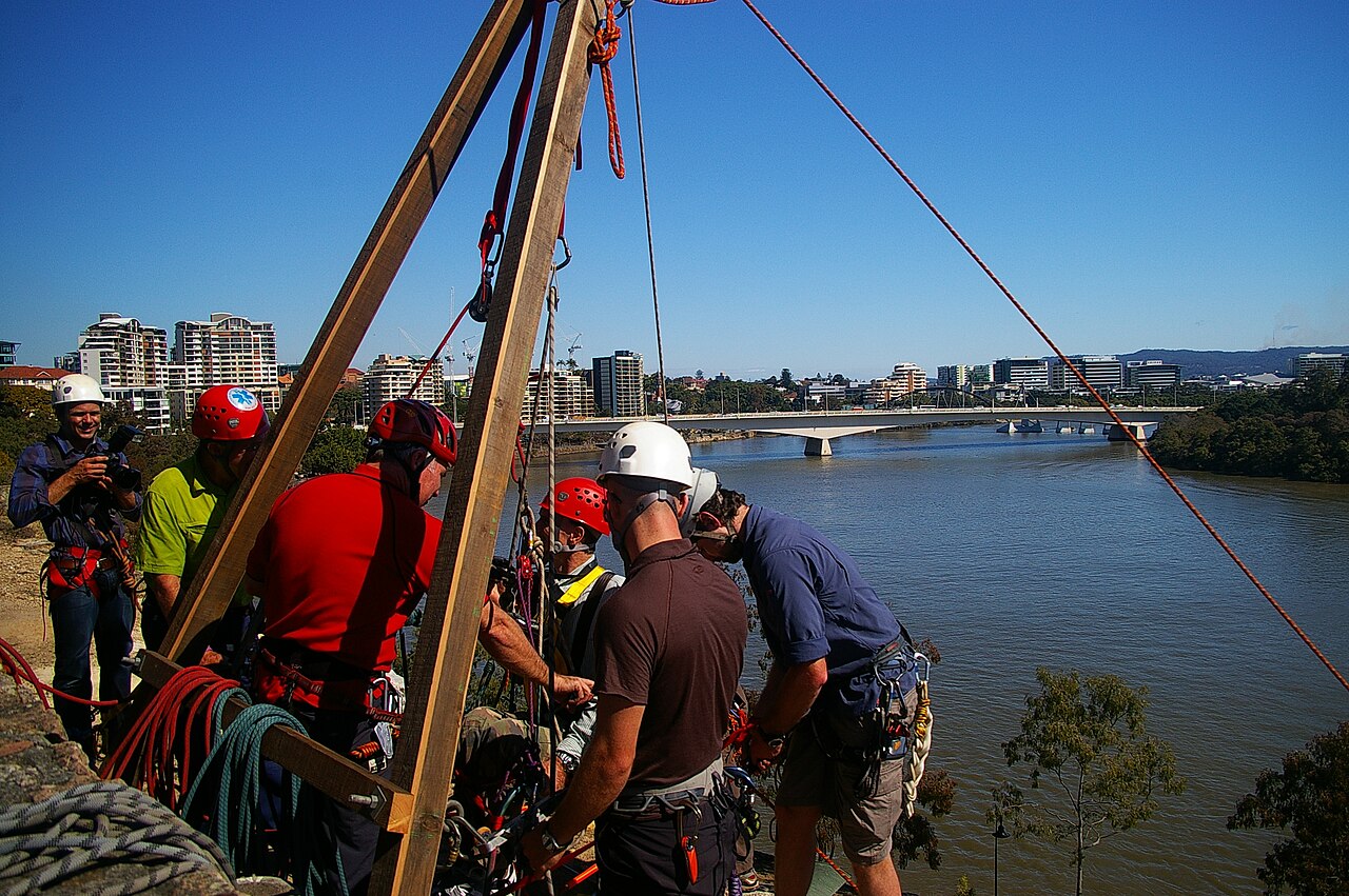 John Robert McPherson · CC BY-SA 4.0 · https://creativecommons.org/licenses/by-sa/4.0 · https://commons.wikimedia.org/wiki/File:NDIS_Promotion_abseiling_Kangaroo_Point_cliffs_River_Tce_Kangaroo_Point_Brisbane_IMGP6077.jpg · Displayed cropped to fit Equipment and preparation at the top of an abseil.