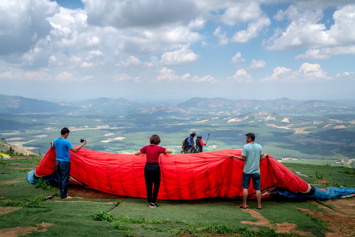 Quang Nguyen Vinh · Pexels License · https://www.pexels.com/license/ · https://www.pexels.com/photo/14022209/ A group laying out a paraglider wing on a grassy hilltop