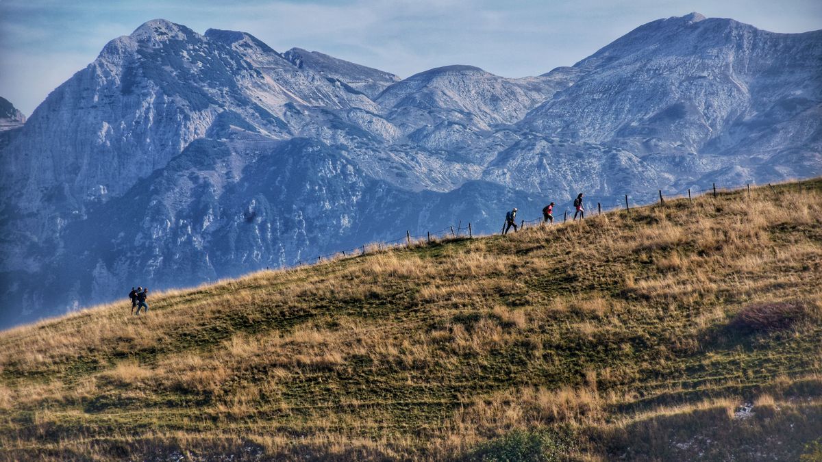 Alessandro Cesarano · Pexels License · https://www.pexels.com/license/ · https://www.pexels.com/photo/18848681/ Walkers crossing open hillside with a mountain backdrop