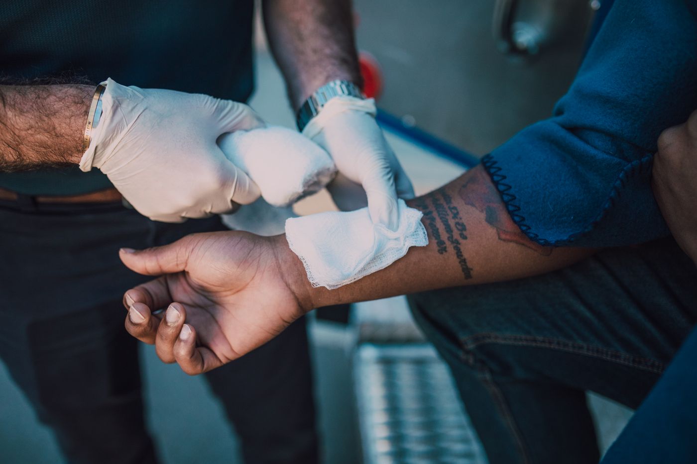 A gloved first aider applying a bandage during a staged care scenario