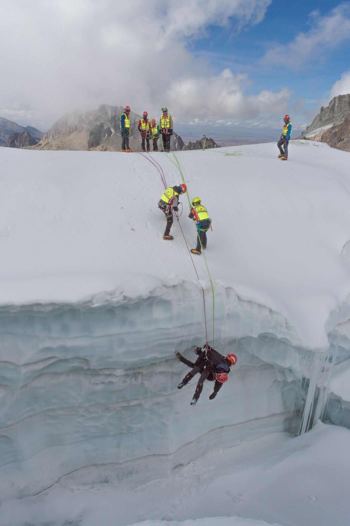 A mountain rescue team working with ropes on steep snow