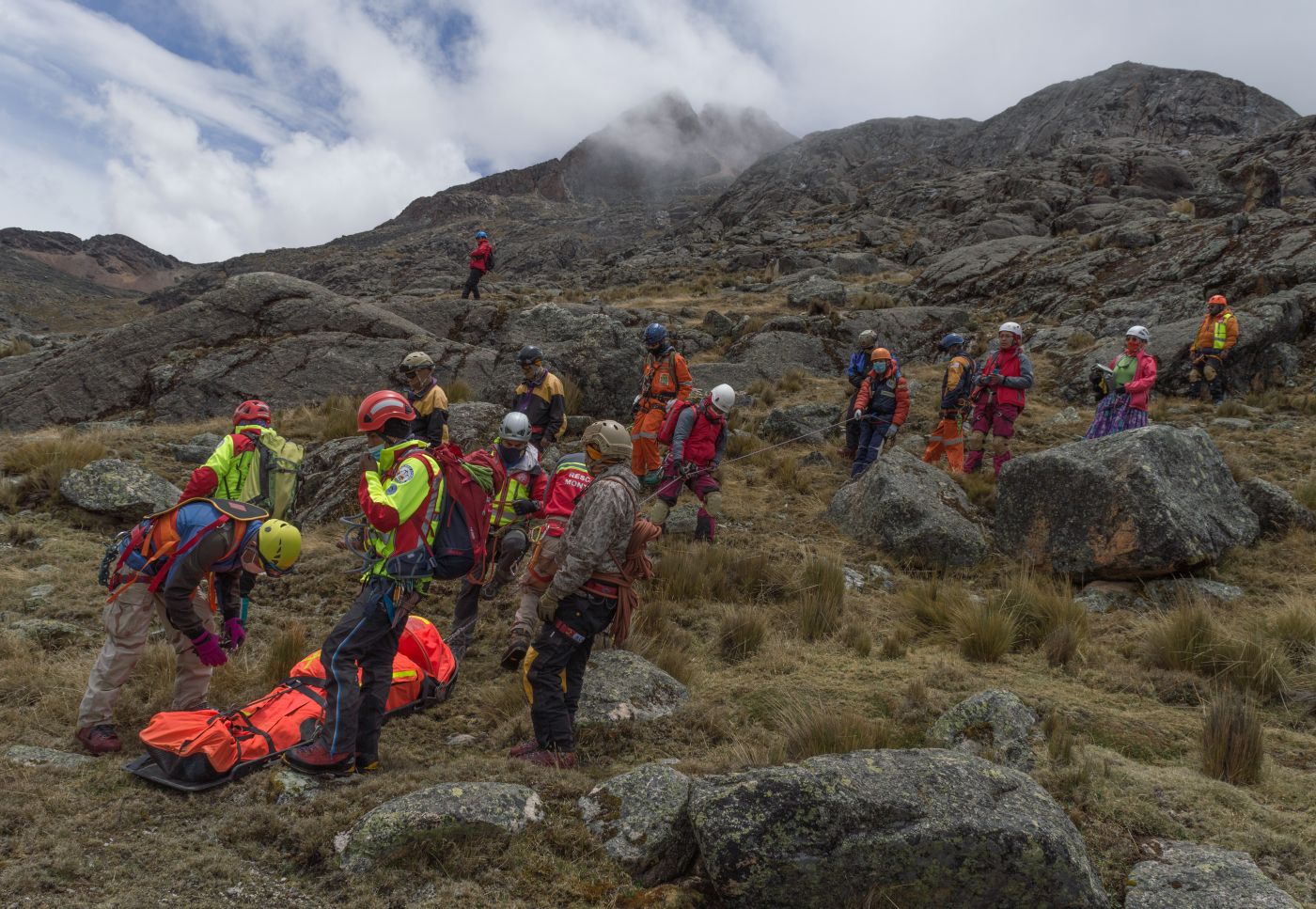 A mountain rescue team coordinating work around a casualty in remote terrain