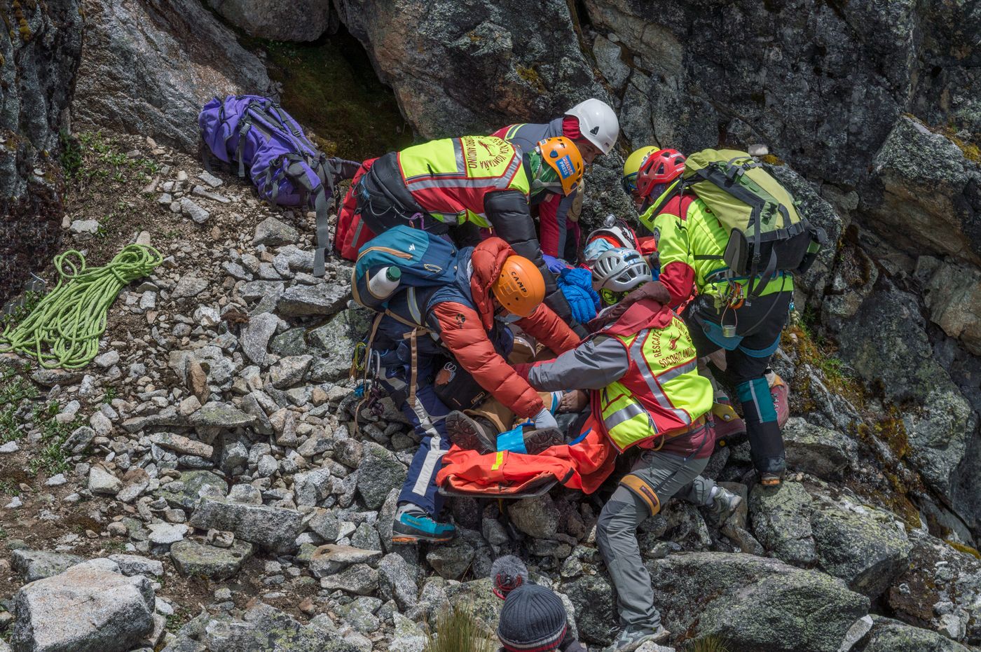 A mountain rescue team preparing a casualty for evacuation on rocky terrain