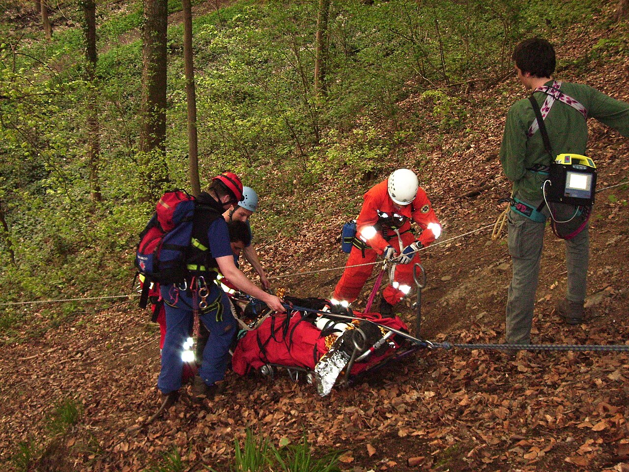 A mountain rescue training team securing a practice casualty to a mountain stretcher