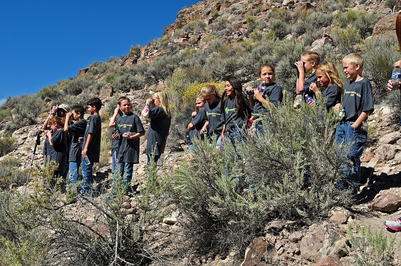 BLM Nevada · Public domain · https://commons.wikimedia.org/wiki/File:Caliente_Elementary_School_students_hiking_(21750479452).jpg · https://commons.wikimedia.org/wiki/File:Caliente_Elementary_School_students_hiking_(21750479452).jpg · Displayed cropped to fit School pupils walking outdoors with accompanying adults