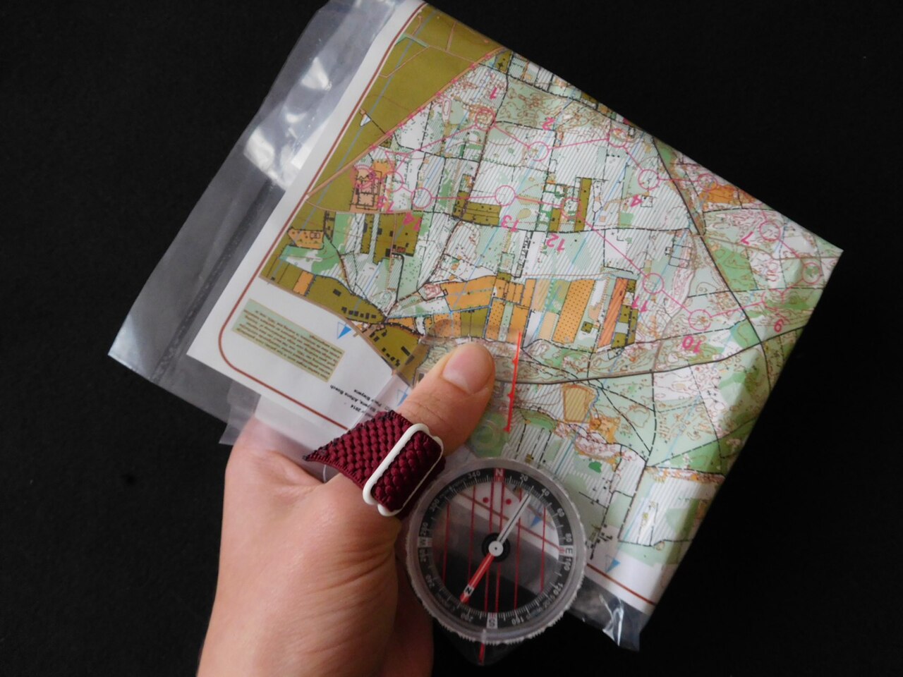 Laurine1122 · CC BY-SA 4.0 · https://creativecommons.org/licenses/by-sa/4.0 · https://commons.wikimedia.org/wiki/File:Het_duimkompas_met_kaart.jpg · Displayed cropped to fit A modern compass held against a detailed map