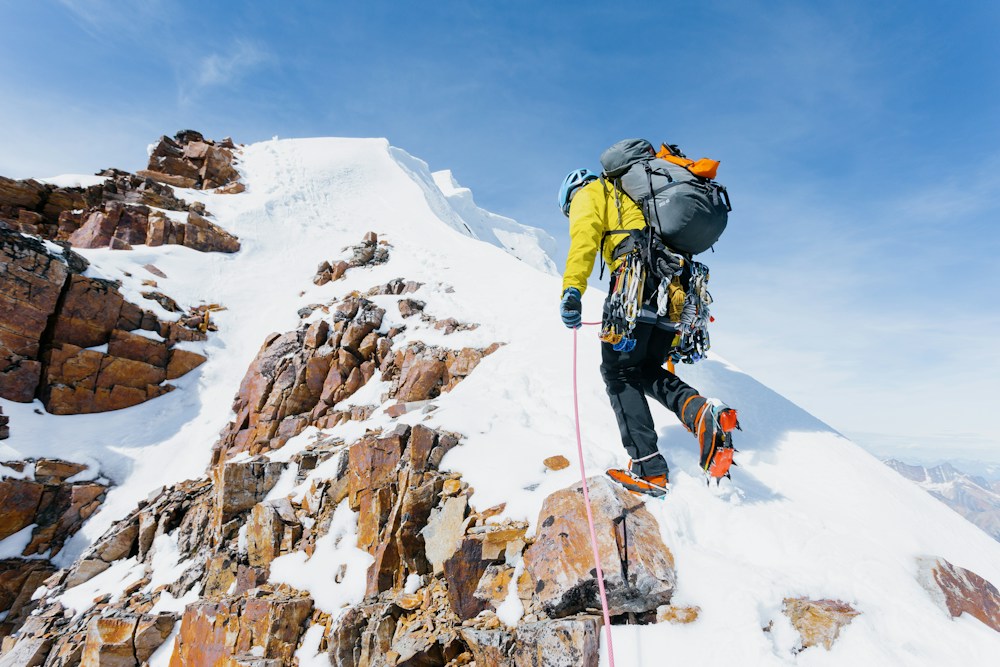 Mountaineer using crampons and an ice axe on a snowy ridge