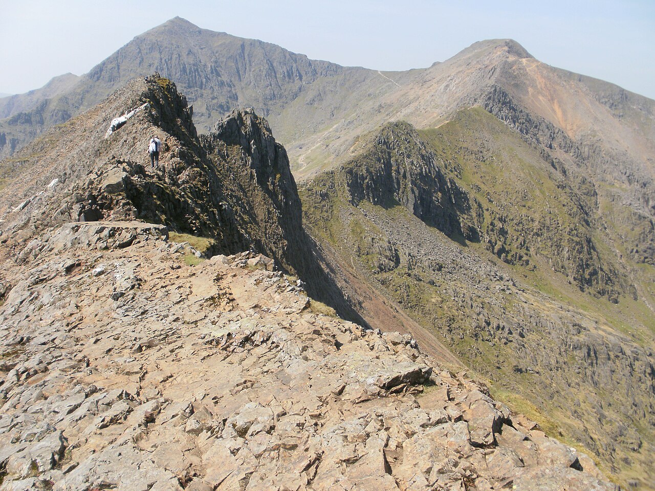 Peter S · CC BY-SA 2.0 · https://creativecommons.org/licenses/by-sa/2.0 · https://commons.wikimedia.org/wiki/File:On_the_Crib_Goch_ar%C3%AAte_-_geograph.org.uk_-_3018569.jpg · Displayed cropped to fit · Displayed cropped to fit A walker negotiating the rocky Crib Goch ridge in Eryri
