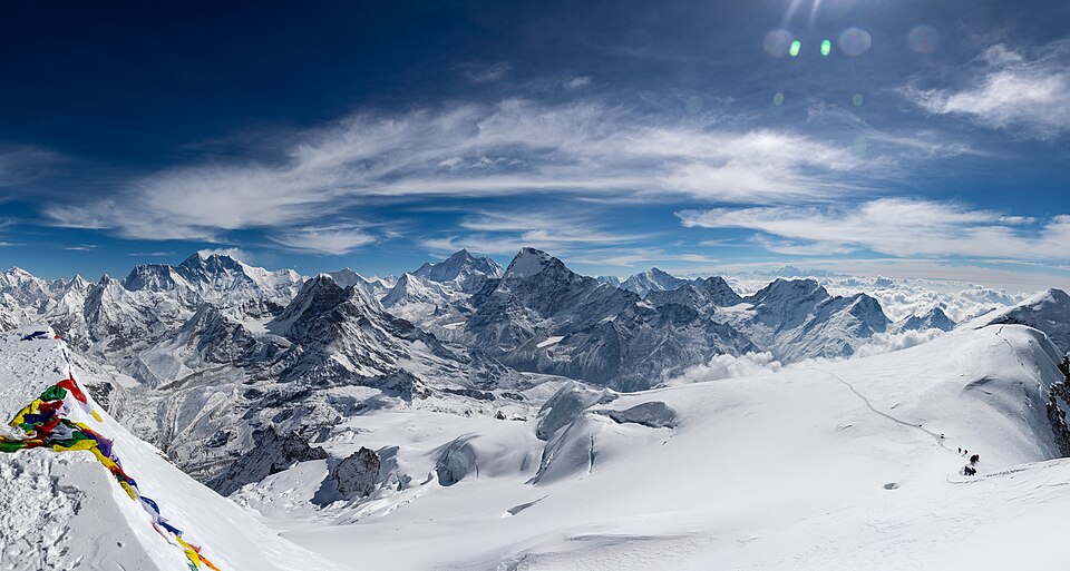 Prayer flags and climbers on the snowy summit of Mera Peak, Nepal