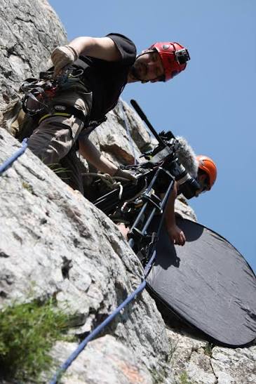 A roped camera team working together on a steep rock face