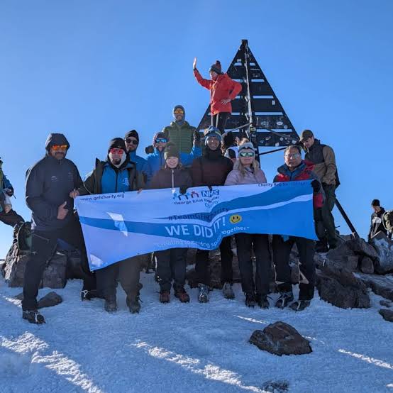 Activity reference photograph supplied for the SOOM website A healthcare charity group on a snowy Toubkal summit with its charity banner