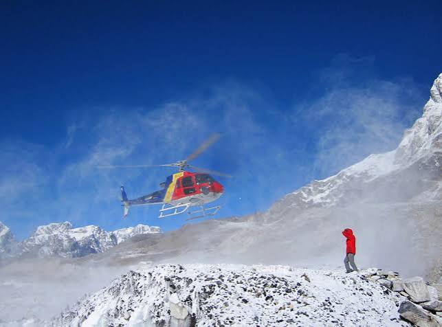 A rescue helicopter approaching snow-covered mountain terrain